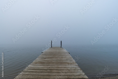 Standing on a dock looking over a lake in the morning with fog 