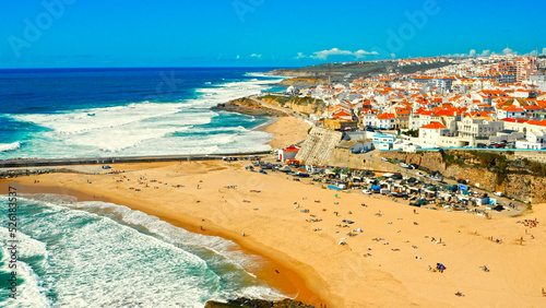 Drone view to Beautiful resort touristic town on ocean background. Aerial view - Beautiful travel destination with sandy beach. Tourist beach for surfing while vacation at Ericeira, in Summer. photo