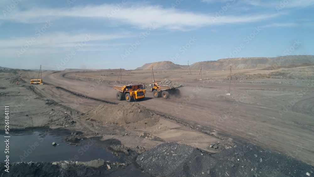 Wide dirt road with huge mining trucks moving towards each other on it Wide dirt road with huge mining trucks moving towards each other on it