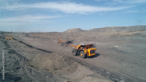Wide dirt road with huge mining trucks moving towards each other on it