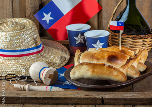 Chilean independence day concept. fiestas patrias. Tipical baked empanadas de pino, wine or chicha, hat and play emboque. Dish and drink on 18 September party, wooden background photo