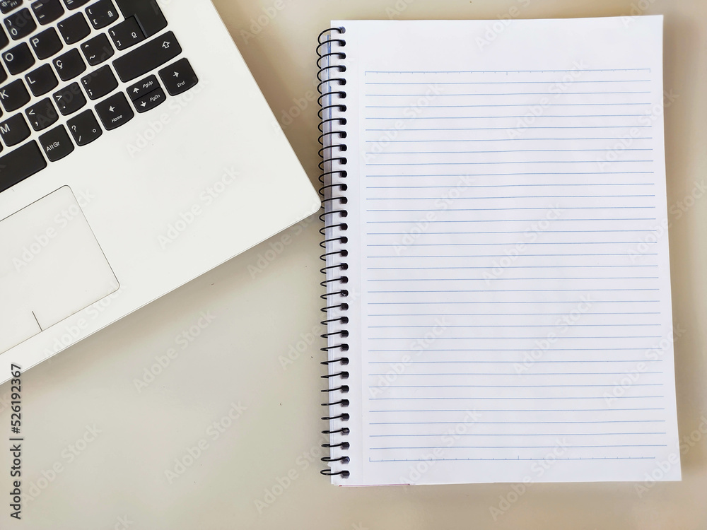 Image showing white office desk and notebook with writing space on the main plane and part of a laptop diagonally Image showing white office desk and notebook with writing space on the main plane and part of a laptop diagonally