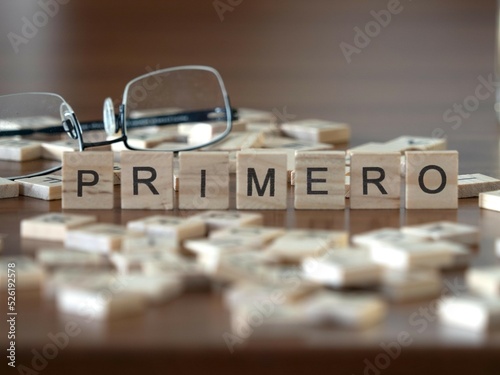 primero palabra o concepto representado por baldosas de letras de madera sobre una mesa de madera con gafas y un libro photo