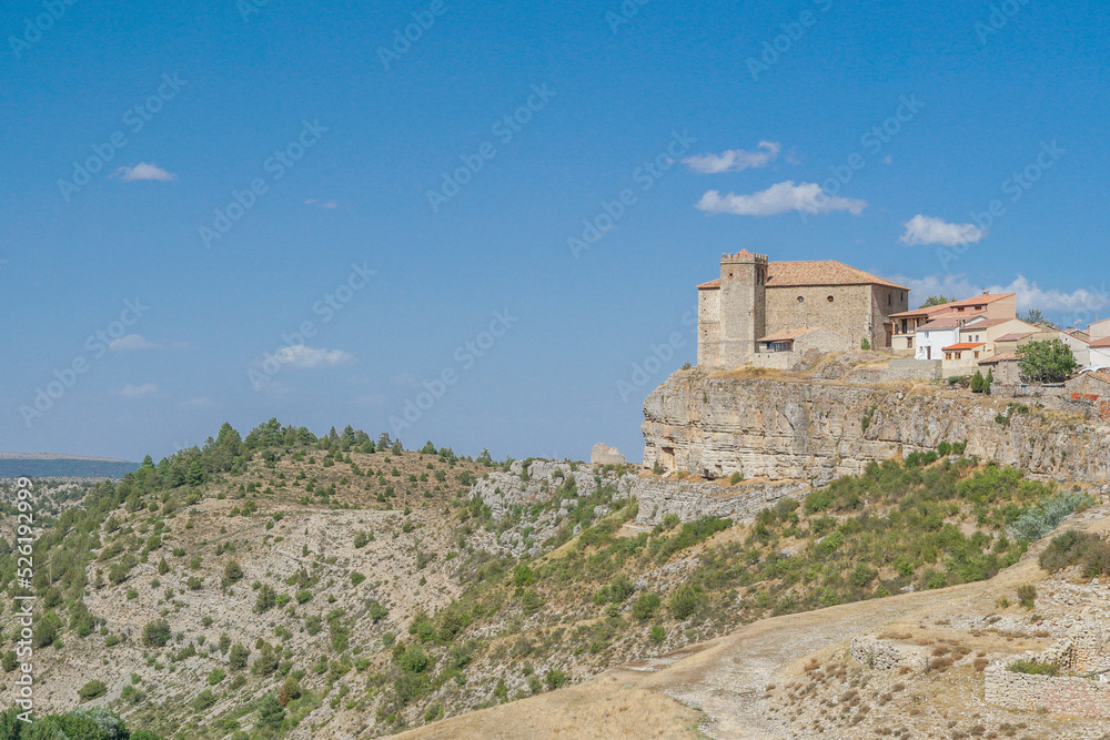 Vista panorámica de Moscardón al borde de un barranco en Teruel con su Iglesia de San Pedro Apóstol sobresaliendo sobre la población