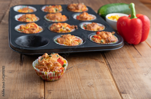 vegetable muffins in a baking form with pepper, corn and zucchini, focus on foreground