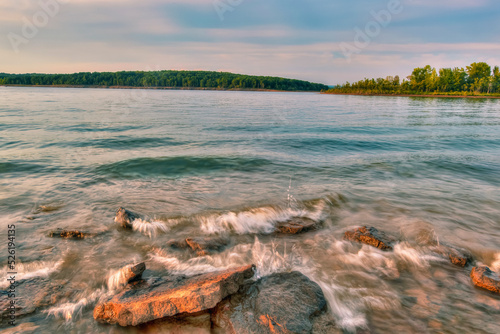 Long exposure of Rocks and sand on the bank of a lake