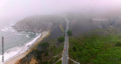 Highway in the mountains with cars running by. Beautiful rocks of Montara, California, USA. Horizon in thick fog. photo