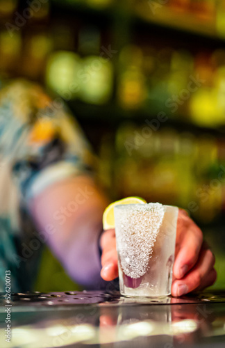 Fototapeta Naklejka Na Ścianę i Meble -  Bartender pouring tequila strong alcoholic drink into small glass