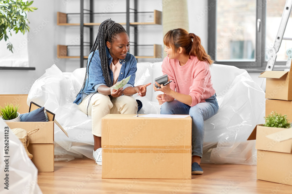 moving, finances and real estate concept - happy smiling women with money, bills and calculator at new home moving, finances and real estate concept - happy smiling women with money, bills and calculator at new home
