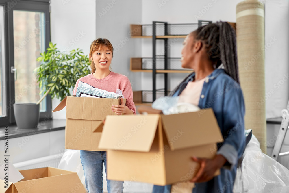 moving, people and real estate concept - happy smiling women with boxes at new home moving, people and real estate concept - happy smiling women with boxes at new home