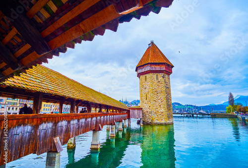 Walk along covered wooden Kapellbrucke (Chapel Bridge) in Lucerne, Switzerland photo