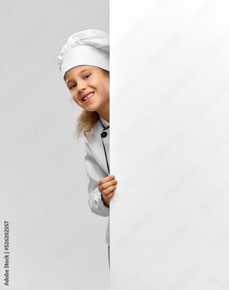 cooking, culinary and profession concept - happy smiling little girl in chef's toque and jacket with white board over grey background cooking, culinary and profession concept - happy smiling little girl in chef's toque and jacket with white board over grey background