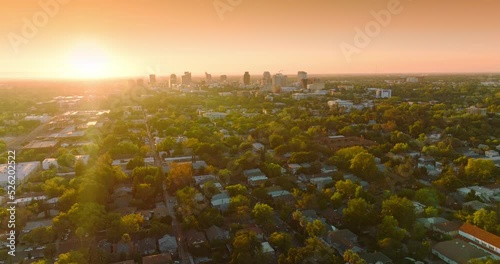 Last rays of setting sun over the beautiful green city. Few multi-storied buildings standing out at the backdrop of orange sky. photo