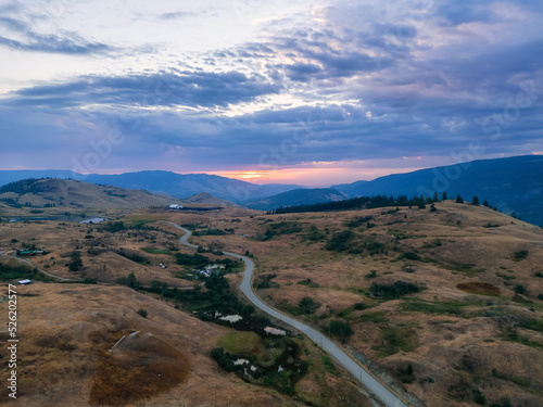 Aerial View of a Scenic Road in the Desert during colorful cloudy sunrise. Near Vernon, Okanagan, British Columbia, Canada.