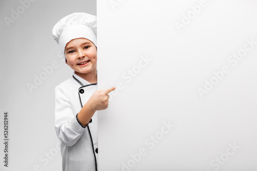 cooking, culinary and profession concept - happy smiling little boy in chef's toque and jacket showing white board over grey background