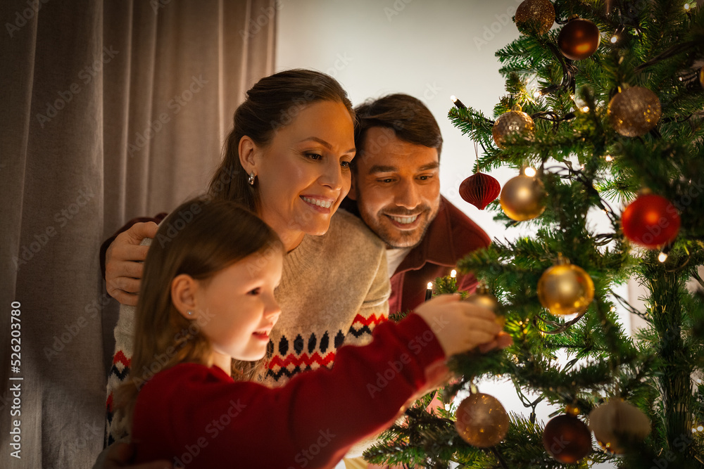 family, winter holidays and people concept - happy mother, father and little daughter decorating christmas tree at home family, winter holidays and people concept - happy mother, father and little daughter decorating christmas tree at home