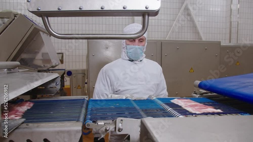 Worker sets up automated bacon cutter removal process in production facility