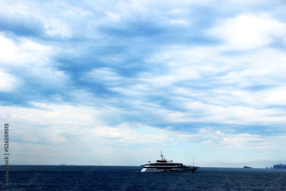 Perfect view in Amalfi coast with a technological boat slightly rippling the deep blue Tyrrhenian sea, a few mountains in the background and a fantastic varied sky full of imposing white clouds Perfect view in Amalfi coast with a technological boat slightly rippling the deep blue Tyrrhenian sea, a few mountains in the background and a fantastic varied sky full of imposing white clouds