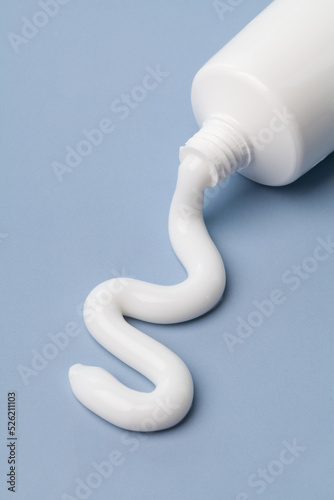white toothpaste squeeze out of tube on blue background.