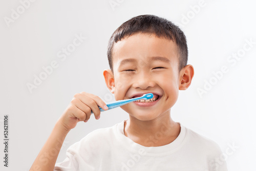 A asian boy brushing his teeth on white background.