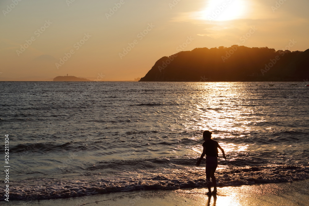 Fototapeta premium 夏休みの思い出、夕暮れの逗子海岸で遊ぶ子どもの後ろ姿