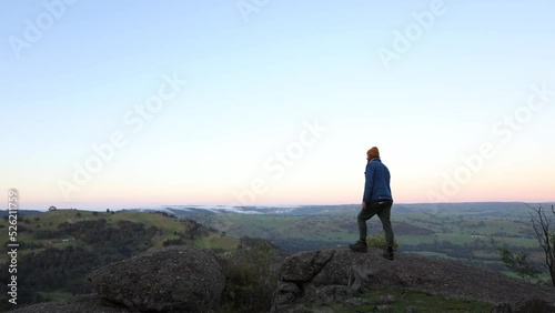 A man at a lookout in the early morning sun with clouds rolling accorss the landscape in Victoria's high country. photo