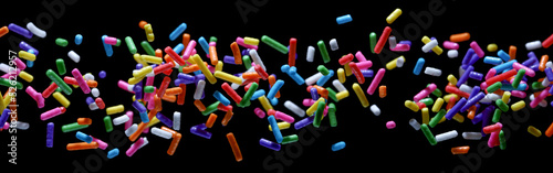 Small sprinkle colorful sugar candies flying sweet food. isolated on a black background 