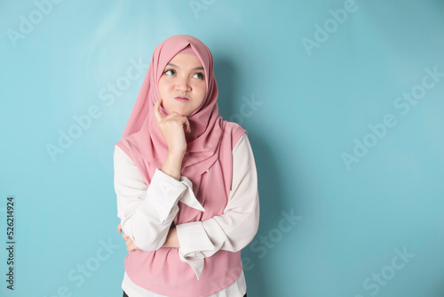 Portrait of a thoughtful young Muslim woman wearing pink hijab looking aside © Reezky
