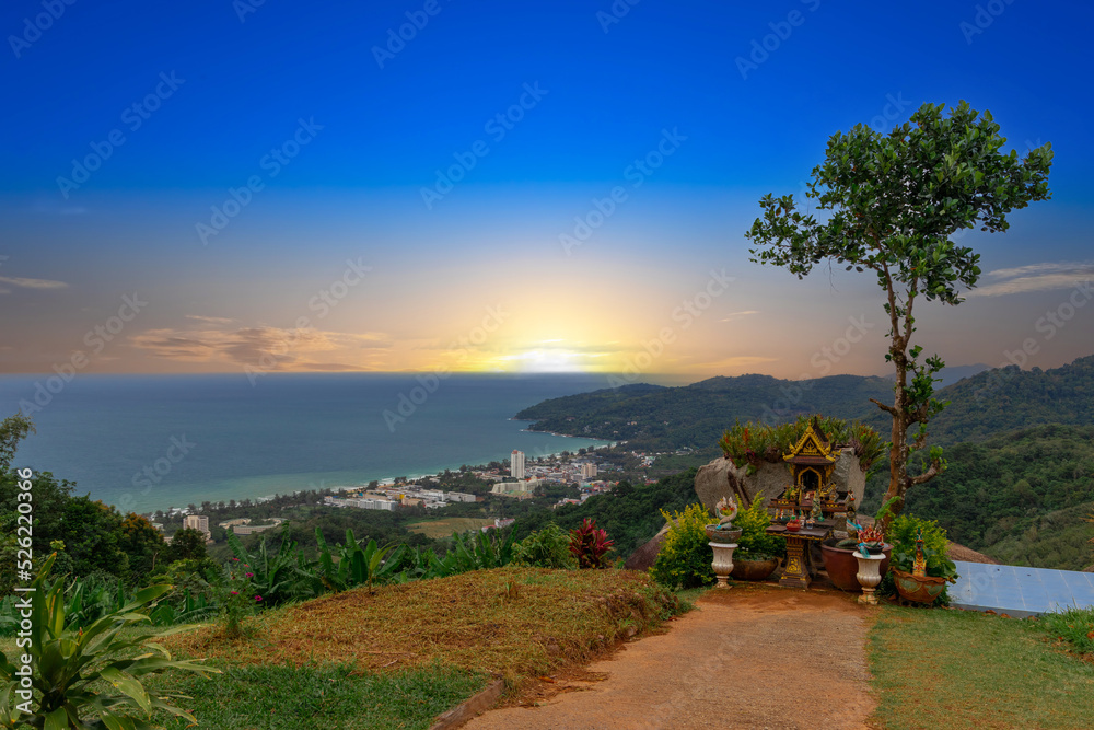 Karon Beach in Phuket Thailand, turquoise blue waters, lush green mountains colourful skies. Phuket is a tropical island many palms
