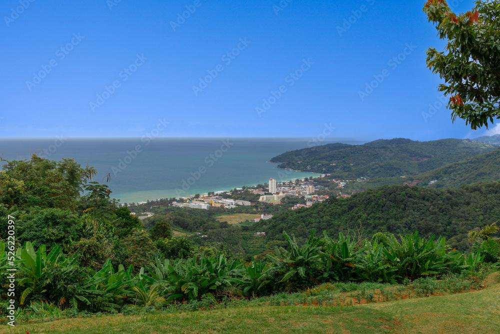 Karon Beach in Phuket Thailand, turquoise blue waters, lush green mountains colourful skies. Phuket is a tropical island many palms