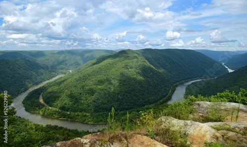 looking out at a horseshoe bend in the new river, railway,   and forested  hills in summer from the grandview main overlook in the new river gorge national park, west virginia