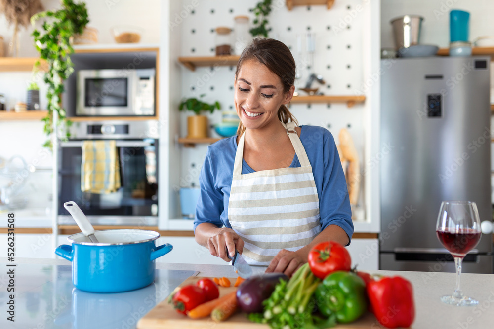 Beautiful young woman stand at modern kitchen chop vegetables prepare fresh vegetable salad for dinner or lunch, young woman cooking at home make breakfast follow healthy diet, vegetarian concept Beautiful young woman stand at modern kitchen chop vegetables prepare fresh vegetable salad for dinner or lunch, young woman cooking at home make breakfast follow healthy diet, vegetarian concept