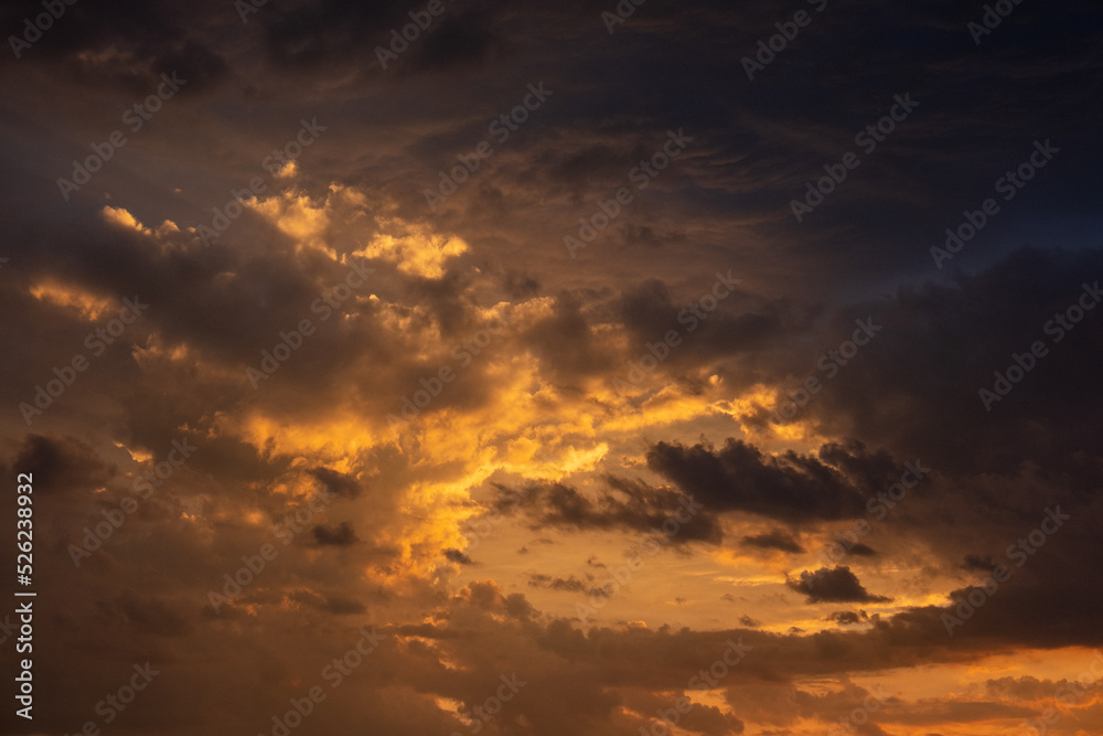 A beautiful sunset with gold, red, yellow and orange sunlight passing through many clouds of different hues. Horizontal photo. Nature. Sky. Cloudy. Background. A beautiful sunset with gold, red, yellow and orange sunlight passing through many clouds of different hues. Horizontal photo. Nature. Sky. Cloudy. Background.