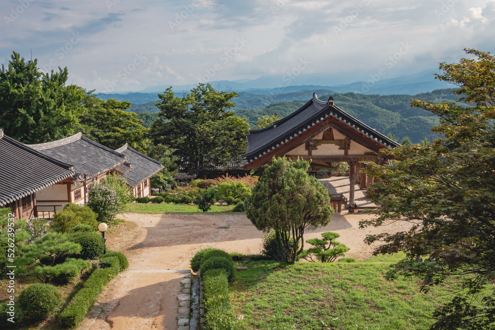 Traditional Korean architecture and lush green forest and mountains at Buseoksa Buddhist temple complex in South Korea on a cloudy day	