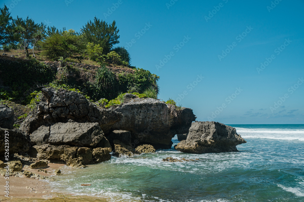 A beautiful and natural white sand beach with rolling waves on the southern coast of Yogyakarta, Indonesia. This exotic beach has great waves and stunning natural scenery A beautiful and natural white sand beach with rolling waves on the southern coast of Yogyakarta, Indonesia. This exotic beach has great waves and stunning natural scenery