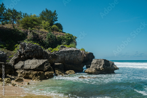 A beautiful and natural white sand beach with rolling waves on the southern coast of Yogyakarta, Indonesia. This exotic beach has great waves and stunning natural scenery