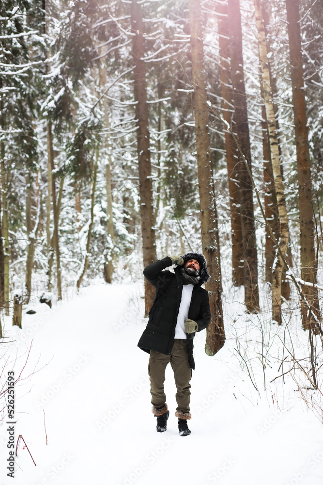 Outdoor portrait of handsome man in coat and scurf. Bearded man in the winter woods.