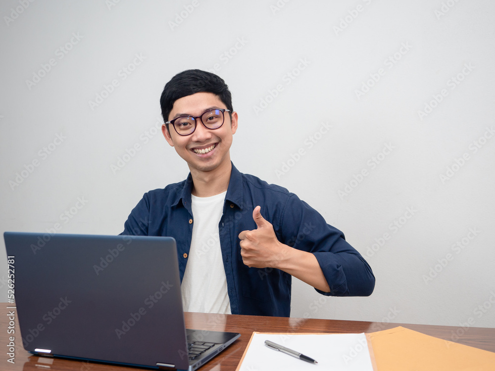 Positive man wear glasses happy smile sit at working table show thumb up Positive man wear glasses happy smile sit at working table show thumb up