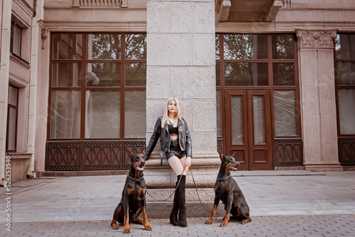 Photography Very beautiful young girl with doberman dogs on the street