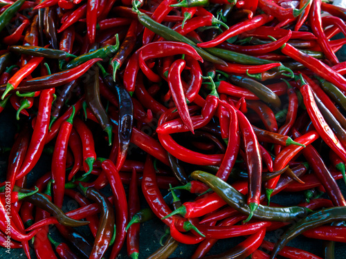 Red hot chilli peppers pattern texture full frame background. A backdrop of fresh Red and black hot chilli peppers. Street vegetable farmer market. Close up group of Red hot chili peppers. © Lyudmila