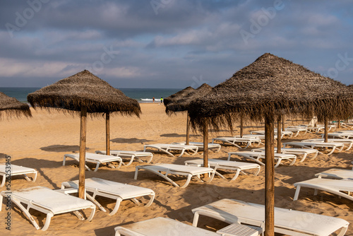 people walking along the beach of La Barrosa seen through the umbrellas of that beach