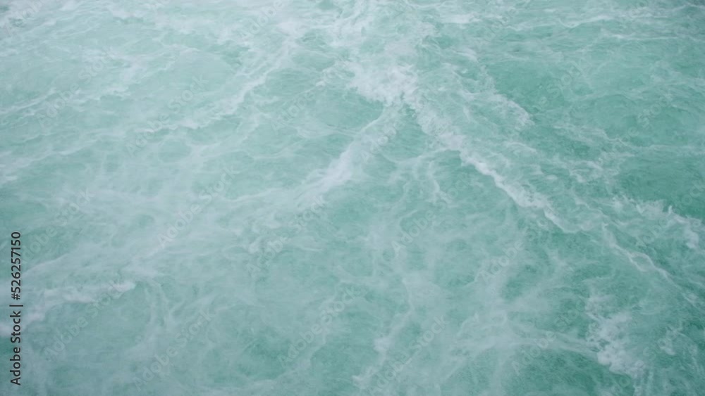 Turquoise Water splashing with foam top view. Ocean water texture. Surface boiling water. Blue ocean wave. View from above. Slow motion.