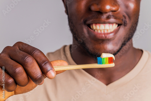 afrian american man holding colorful rainbow toothbrush in gray backgroung photo