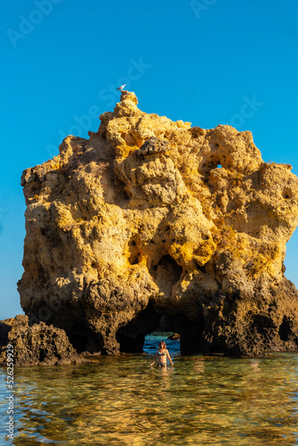 A tourist in the water next to the rocks at Praia dos Arrifes, Algarve beach, Albufeira. Portugal photo