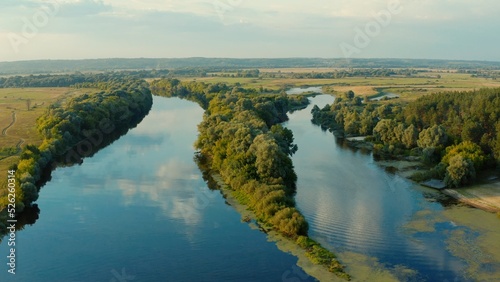 Aerial view above a beautiful landscape with a  river while sunset. Aerial view from drone flies over a beautiful summer landscape.