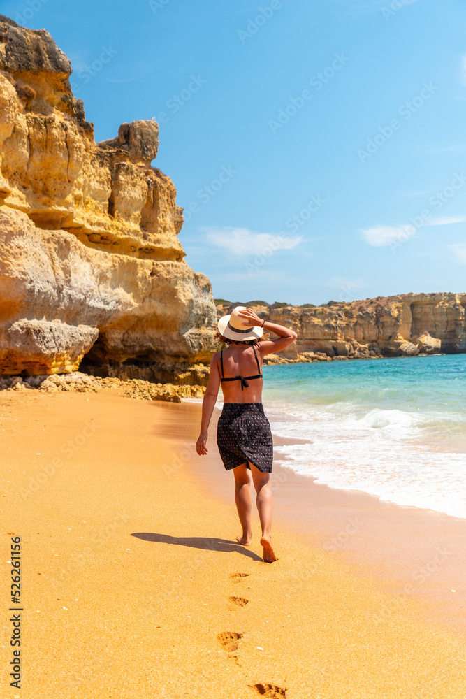 A female tourist strolling on the beach at Praia da Coelha, Algarve, Albufeira. Portugal