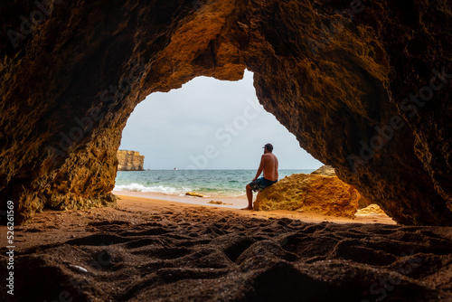 A man in the natural cave in the Algarve on the beach at Praia da Coelha, Albufeira. Portugal