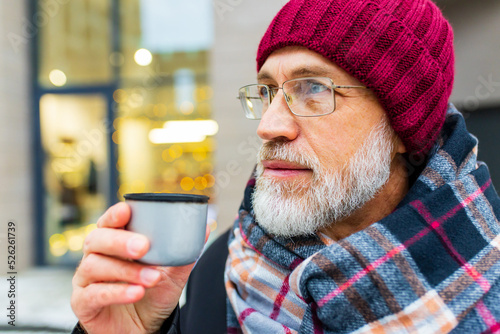 goog looking mature man drink hot tea in city street at winter