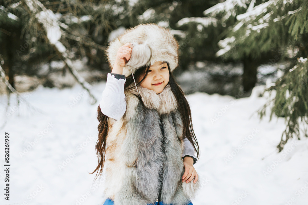 portrait of beautiful cute little Asian girl in fur coat and fur hat standing in snowy forest in winter, winter holidays and having fun, Christmas vacation portrait of beautiful cute little Asian girl in fur coat and fur hat standing in snowy forest in winter, winter holidays and having fun, Christmas vacation