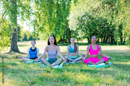 four young women group diverse people asian woman, mixed race female, woman with bionic prosthetic leg do sport yoga morning mats outside in park, healthy lifestyle, fitness, training and stretching